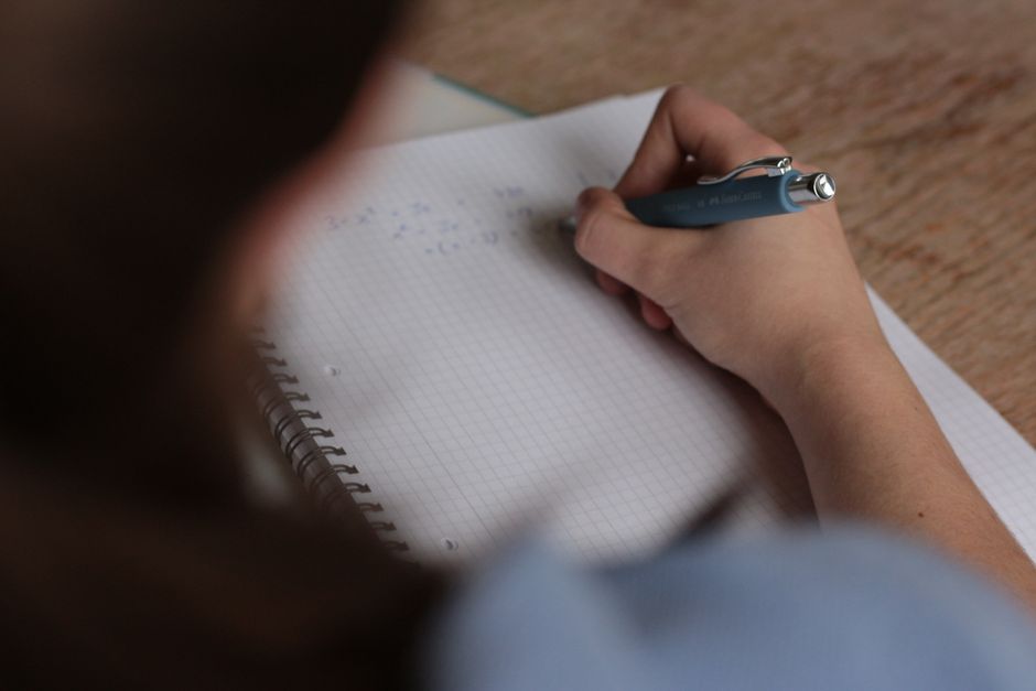 Siswa menulis catatan pelajaran dengan pena di buku