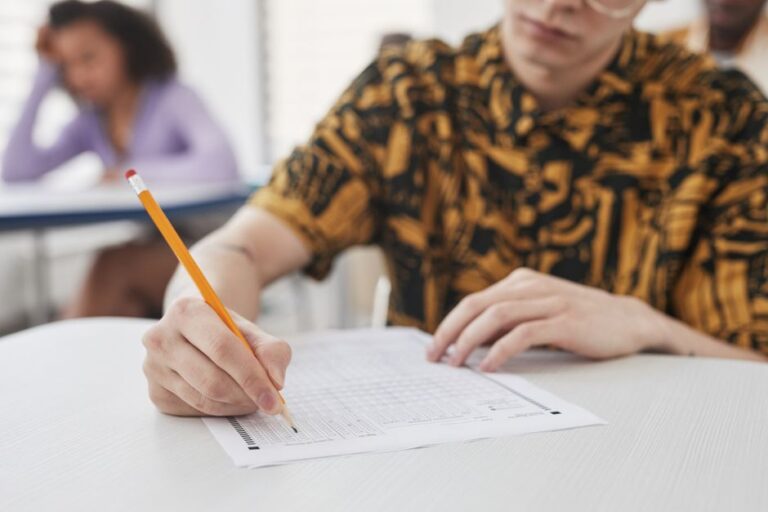 Siswa menulis jawaban ujian dengan pensil dan kertas